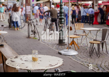 Outdoor vintage furniture of cafe or coffee shop located at old town square with blur background crowd of tourists in Düsseldorf, Germany. Stock Photo