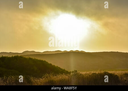 Sun breaking through clouds over hills at sunset. Sun breaking through clouds over hills at sunset.