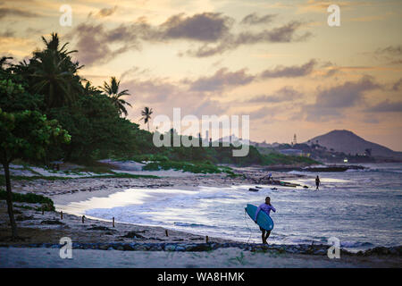 Surfer is seen carrying his board at Playa Long beach, in Cosita Rica area, Puerto Plata, Dominican Republic Stock Photo