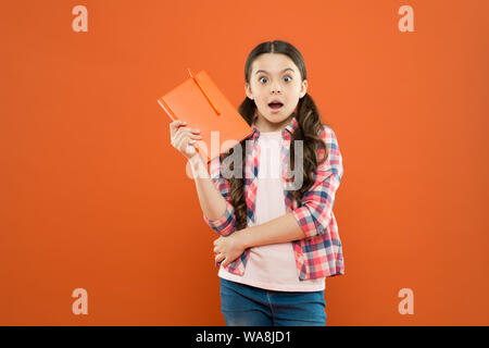 Studying is exciting. Girl cute kid study with book. Interesting book. Did you know. Pupil with work book. Literature and writing lesson. Schoolgirl with notebook doing homework. Learning language. Stock Photo