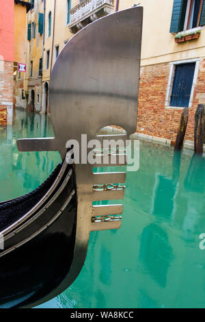 Iron prow-head of a gondola, called fero da prorà or dolfin.  The six forward prongs are called rebbi. On the Rio del Bareteri canal, Venice, Italy Stock Photo