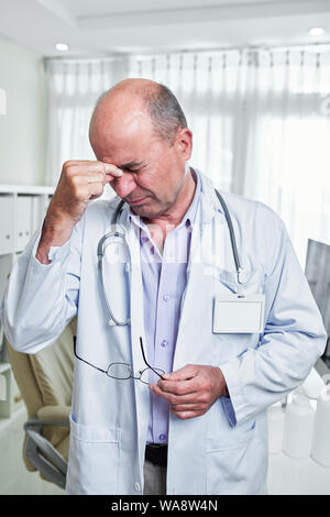 Stressed doctor suffering from severe headache after difficult day at work Stock Photo