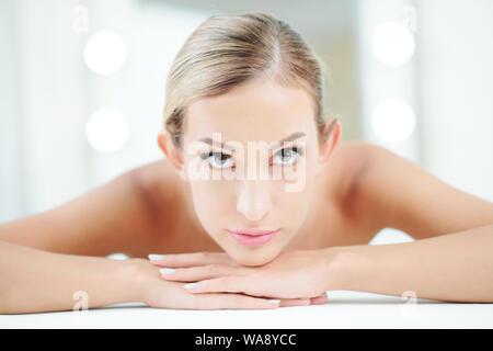 Pretty female spa salon client lying on massage bed and looking at camera Stock Photo