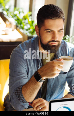 Serious bearded man sitting with a coffee cup Stock Photo