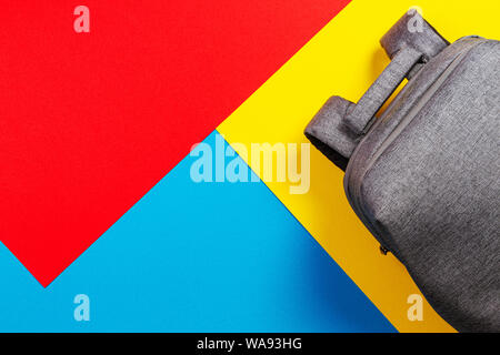 Top view of gray backpack on yellow, blue and red background Stock Photo