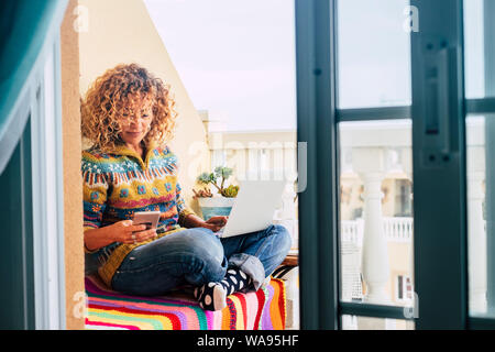 People at home with technology concept - full of color image for middle age woman working freedom at laptop outdoor in the terrace,  beautiful blonde Stock Photo