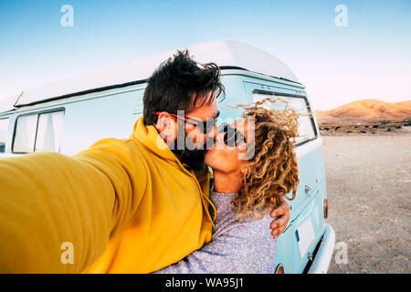 Love and relationship concept with couple of traveler with old vintage van kissing and taking a selfie picture -alternative lifestyle and. vacation wi Stock Photo