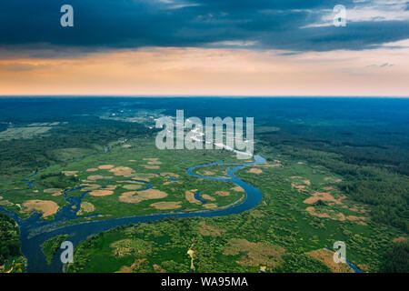 Aerial View. Sunset Sky Above Green Forest, Meadow And River Landscape In Sunny Evening. Top View Of European Nature From High Attitude In Summer Sunr Stock Photo