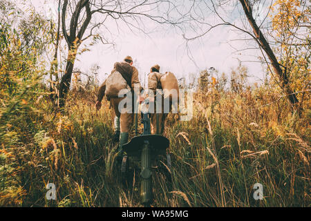 Two Reenactors Dressed As Russian Soviet Red Army Soldiers Of World War II Walking With With Maxim's Machine Gun Weapon In Autumn Meadow, Forest Stock Photo