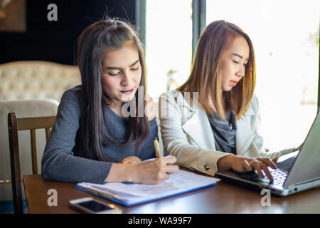 Two Asian business women using notebook working and Discussion of the important contract at office Stock Photo