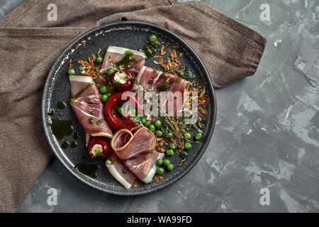 Italian prosciutto crudo and jamon with rosemary. Raw ham on a concrete gray background. Close-up Stock Photo