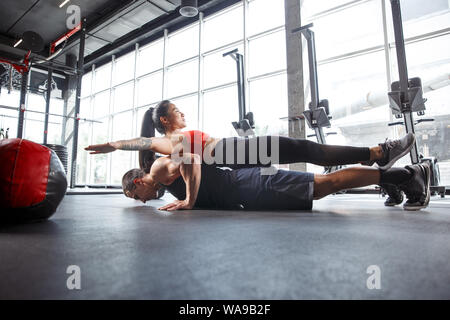 A muscular athletes doing workout at the gym. Gymnastics, training, fitness workout flexibility. Active and healthy lifestyle, youth, bodybuilding. Doing exercises together, training in push ups. Stock Photo