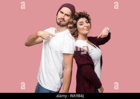 Portrait of satisfied successful couple of friends in casual style standing back to back, pointing themself with proud face and looking at camera. Iso Stock Photo