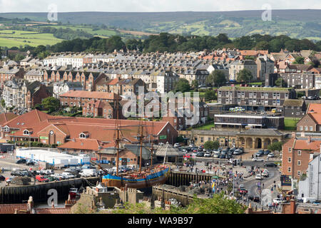 Whitby townscape with replica Captain Cook's ship Endeavour and rows of terraced houses to the north west of the town, in Yorkshire, England, UK Stock Photo