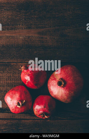 Four ripe pomegranate on rustic wooden table Stock Photo