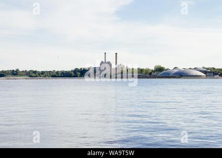 Beautiful shot of a river with factory pipes and modern round buildings on the side Stock Photo