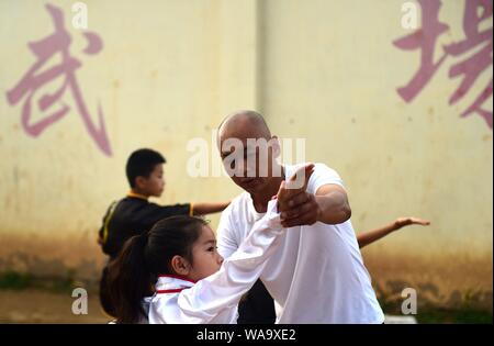 A Chinese child practices Chinese martial arts or kungfu directed by Chen Honglin, a well-known local practitioner, to maintain fitness during the sum Stock Photo