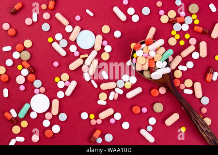 Different colorful pills and capsules in wooden spoon. Global pharmaceutical industry for billions dollars per year. Pharmaceutical drugs. Isolated on Stock Photo