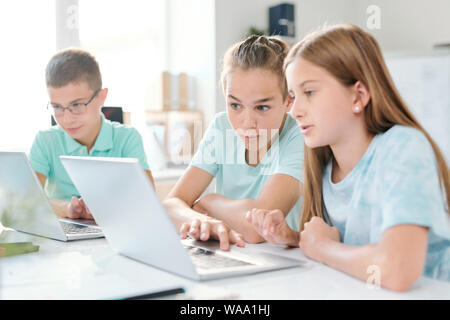 Middle school boy and girl looking at curious stuff on laptop display Stock Photo