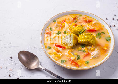 Mexican corn soup with pepper and chicken on a gray texture background with a spoon Stock Photo