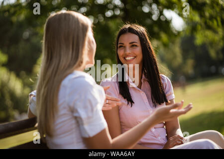 Two friends are sitting in park and talking. Stock Photo