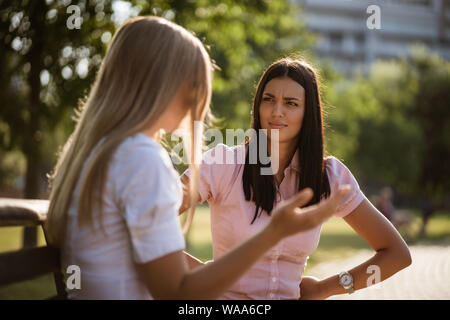 Two friends are sitting in park and talking. Stock Photo