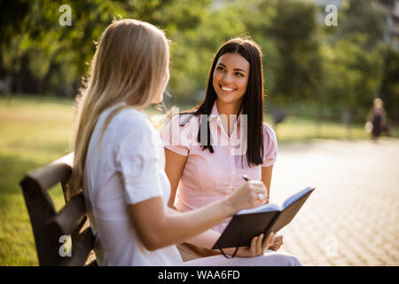 Two business colleagues are sitting in park and talking. Stock Photo
