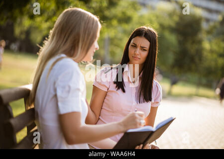Two business colleagues are sitting in park and talking. Stock Photo