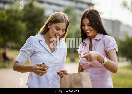 Two friends in park after shopping. Stock Photo