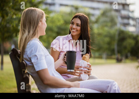 Two business colleagues are sitting in park and talking on break. Stock Photo