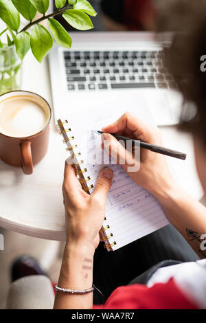 Young female manager making notes in notebook while organizing work Stock Photo