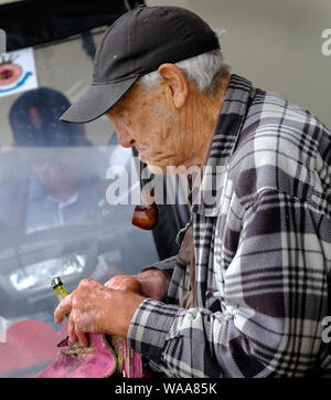 Old man in invalid carriage with cigarette lighter. Stock Photo