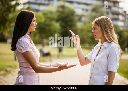 Two female friends are arguing in park. Stock Photo