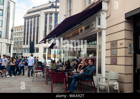 London / UK - July 18, 2019: people seating outside Pret a Manger drinking coffee and relaxing. Pret is a popular international sandwich shop chain, b Stock Photo