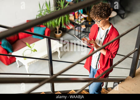 Young female fashion designer in smart casualwear using digital tablet Stock Photo