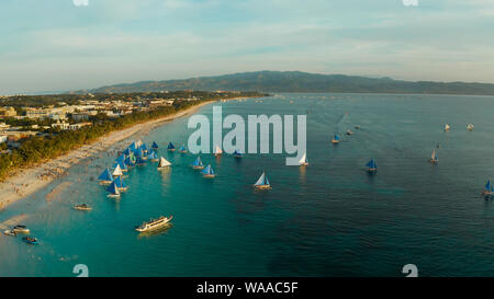 Aerial view of sailing boats on the sandy beach of Boracay Island at sunset time. Tropical white beach with sailing boat. Summer and travel vacation concept. Stock Photo