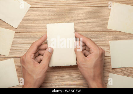 Old photo in the hands of man. Empty template for picture, mock-up. Wooden background Stock Photo
