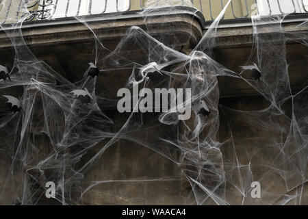 Artificial cobwebs and paper black bats on old house wall, halloween decorations Stock Photo