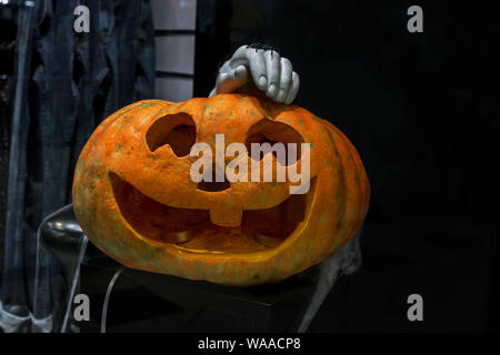 Halloween carved pumpkin Jack o' lantern and mannequin hand with spider in dark room Stock Photo