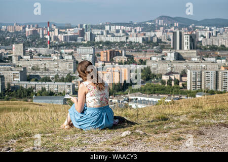 Young woman taking notes in a field above Krasnoyarsk, Siberia, Russia Stock Photo