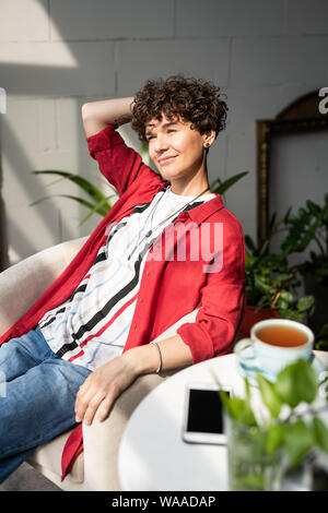 Serene and satisfied woman in stylish casualwear relaxing in armchair Stock Photo