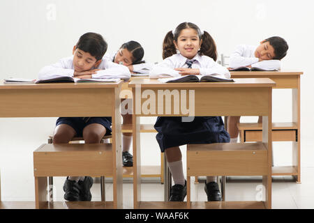Sleeping students and diligent pupil in a school classroom Stock Photo