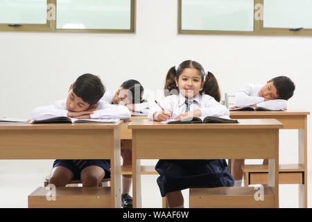 Sleeping students and diligent pupil in a school classroom Stock Photo