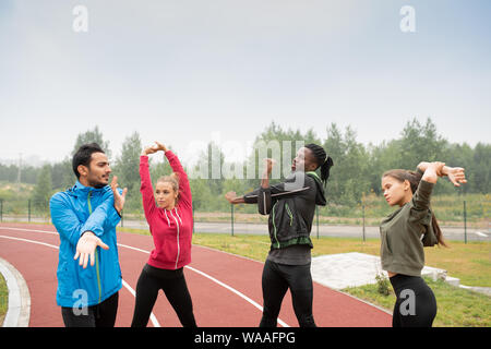 Group of young intercultural friends in activewear doing warming up exercises Stock Photo