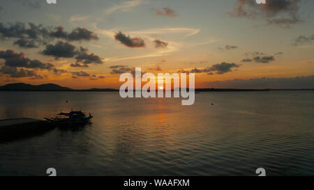 Sunset above the sea surface with waves, aerial view. Reflected sun on a water surface. Balabac, Palawan, Philippines. Sunset over ocean. Stock Photo