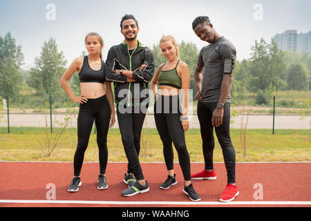 Row of happy young intercultural friends in activewear looking at you Stock Photo