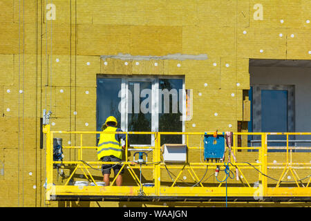 High-altitude work on the external walls of glass wool insulation and plaster Stock Photo