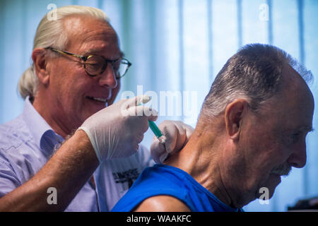 Hohen Wangelin, Germany. 25th June, 2019. The 74-year-old country doctor Lothar Kruse gives an injection to the patient Heinz Wiedemann in his practice. The general practitioner has been treating patients from the region in his practice in Hohen Wangelin for 40 years. At the end of 2019, Kruse wants to give up his practice, but has so far unsuccessfully sought a successor. Credit: Jens Büttner/dpa-Zentralbild/ZB/dpa/Alamy Live News Stock Photo