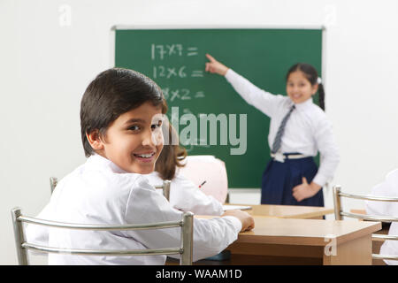 Schoolgirl looking back towards camera and schoolgirl teaching her ...