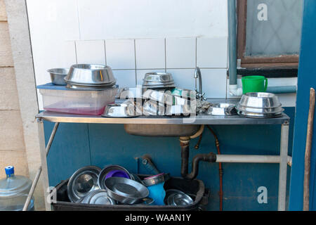 A close up view of metal dogs dishes piled up on a washing sink waiting to be cleaned Stock Photo